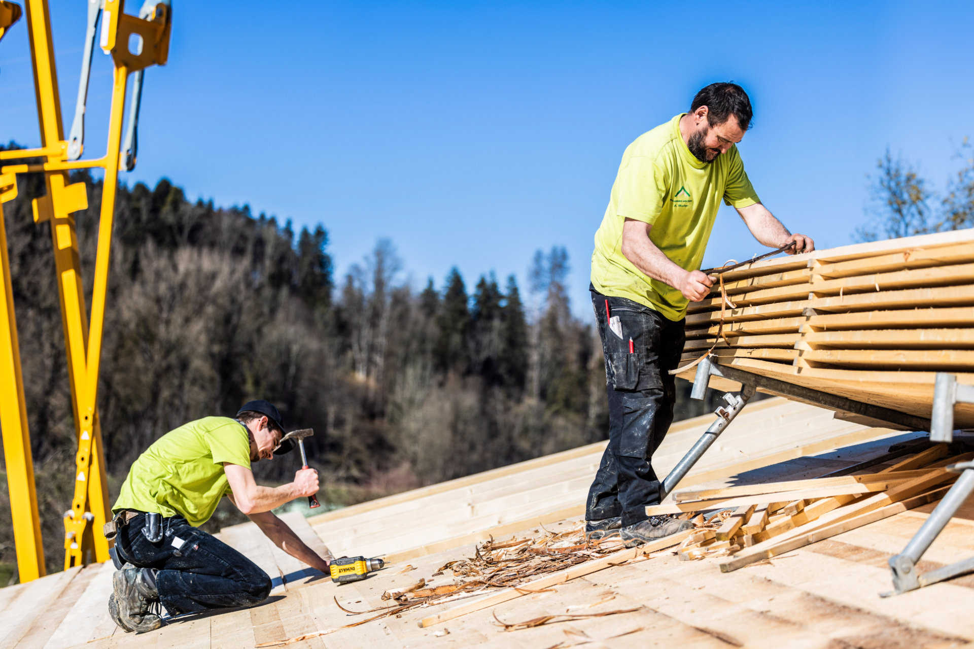 Holzarbeiten auf dem Dach Zwei Mitarbeiter von Allgäuer Holzbau führen Holzarbeiten auf einem Dach aus