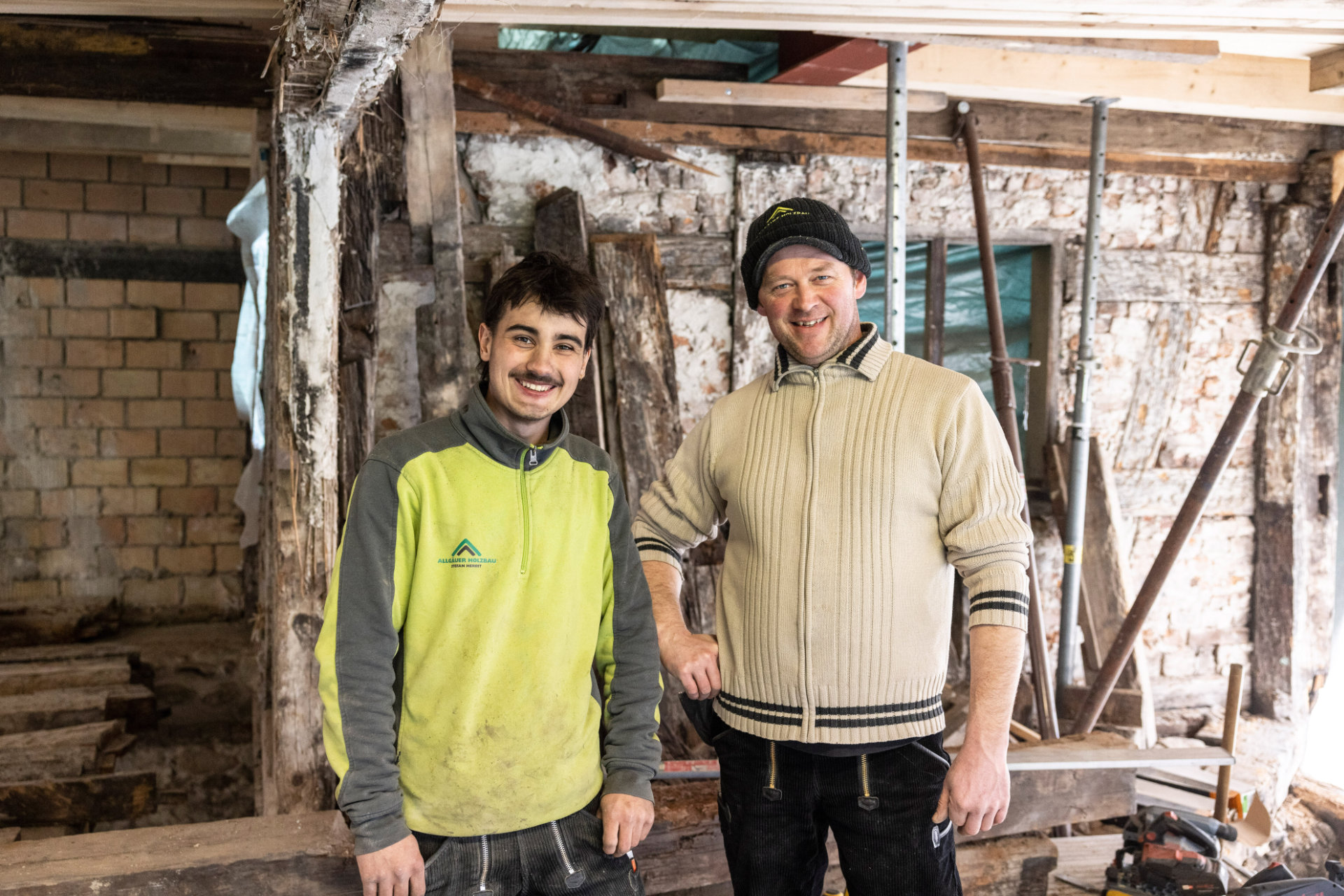 Allgäuer Holzbau auf der Baustelle Zwei Mitarbeiter stehen auf einer Baustelle nebeneinander