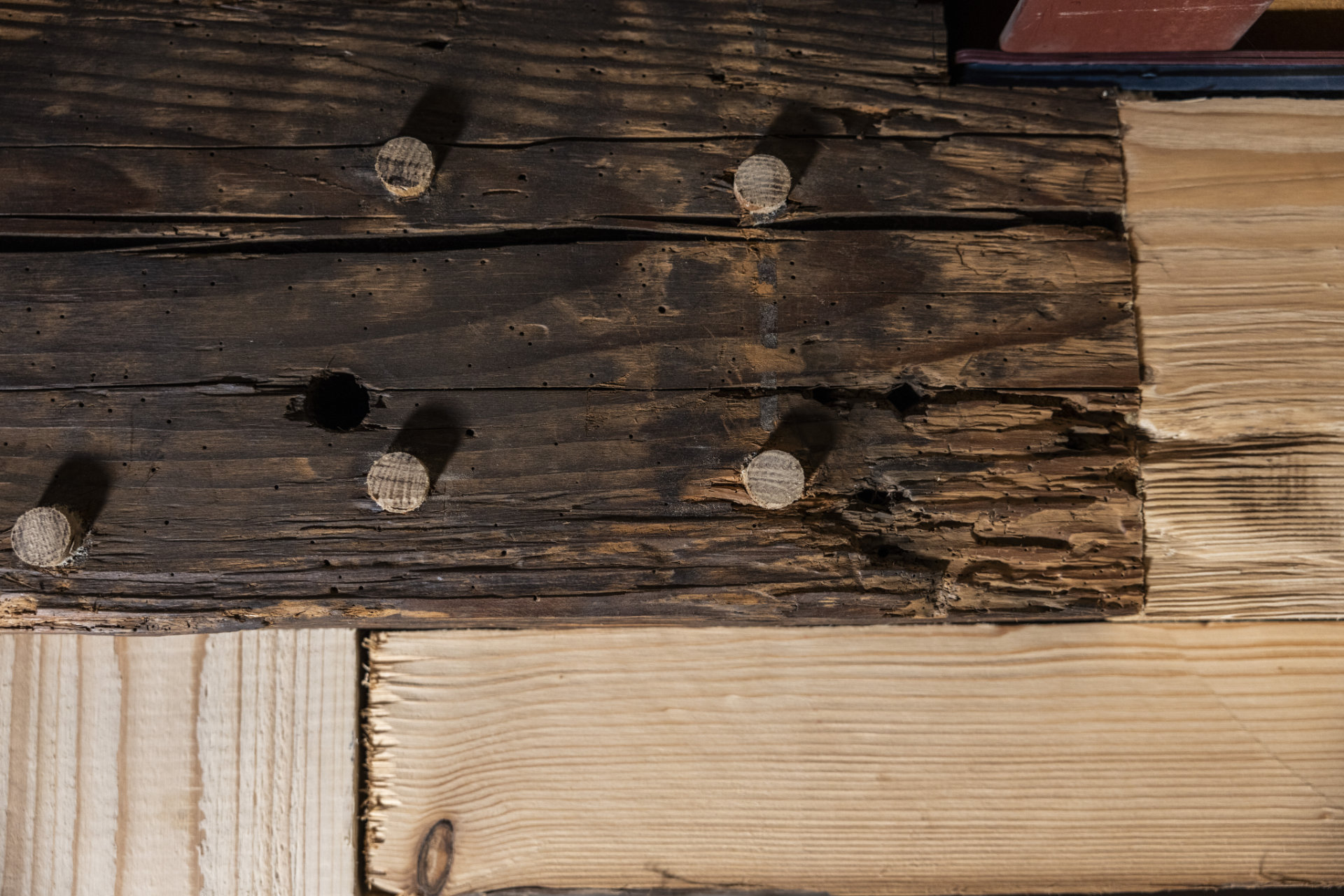 Altes und neues Holz kombiniert Ein alter Holzbalken wird mit Holzstiften vor einen neuen montiert.