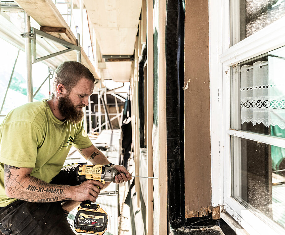 Ein Mitarbeiter von Allgäuer Holzbau arbeitet an einer Fassade
