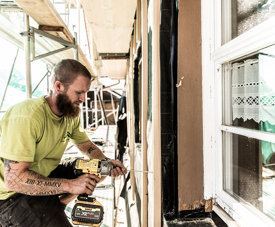 Ein Mitarbeiter von Allgäuer Holzbau arbeitet an einer Fassade