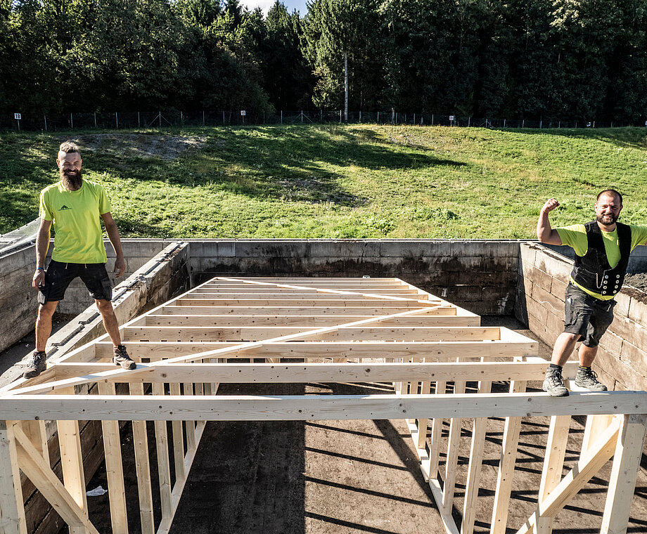 Zwei Mitarbeiter von Allgäuer Holzbau stehen auf einem Holzgerüst