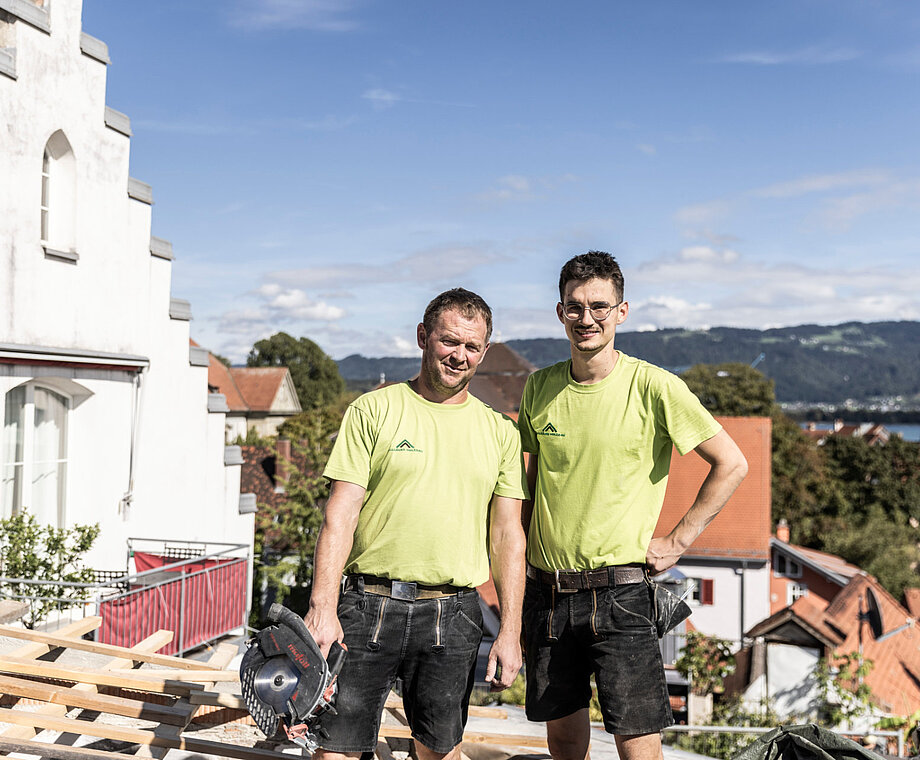 Zwei Mitarbeiter von Allgäuer Holzbau stehen auf einem Dach
